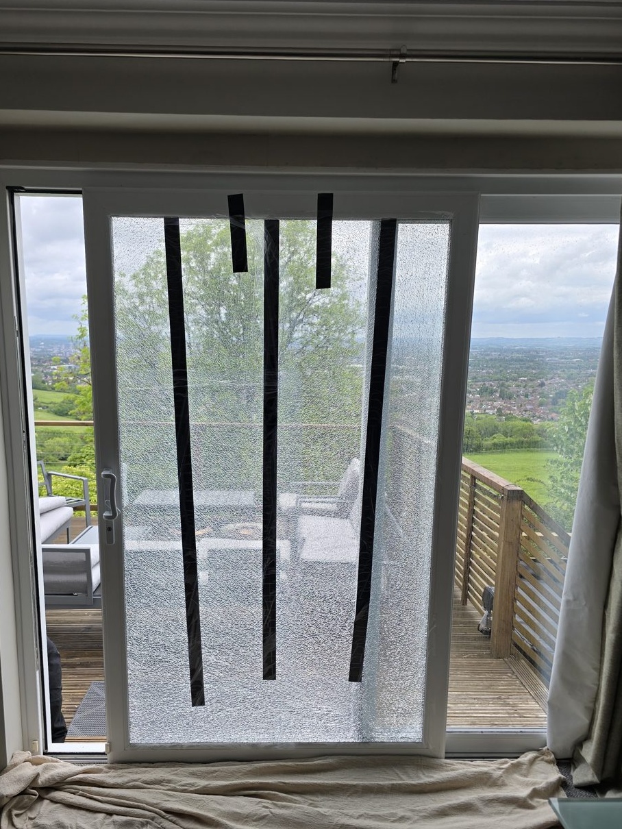 Smashed patio door glass taped up at a house in Dundry, Bristol, before replacement